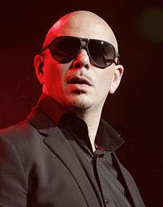 A bald man is wearing dark glasses and black tuxedo