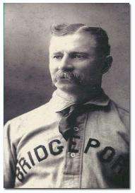 A mustachioed man wearing a baseball jersey with "BRIDGEPORT" across the chest