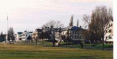 Wintertime photograph of wood-frame Army buildings along the parade ground at Fort Worden.