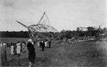 A photograph showing the wreckage of R101 in the background with a number of onlookers to the left of the image