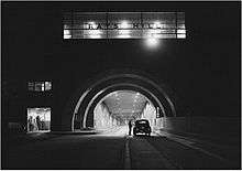 Black-and-white photo of highway tunnel at night