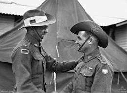 Two men wearing military uniforms shake hands