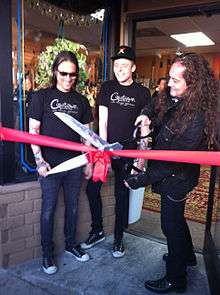 a rock star cuts a ribbon at a ceremony.