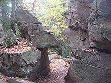 Photo of a path passing through a narrow gap between angular rocks; the two sides of the gap look as if they once fit together.