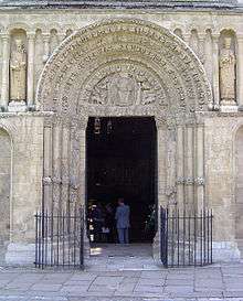 An ancient doorway has sculptured jambs and the figure of Christ within the arch over the lintel.