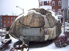 a boulder partially covered in snow with a large plaque on it.
