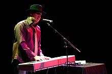 A picture of a man singing and playing the keyboard