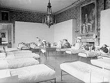 A room converted into a hospital ward with nurses and patients in beds