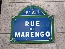 Blue street sign with green edges. It says in white: "1er Arrt" and below "RUE DE MARENGO".