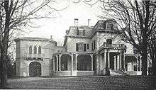 A two-story Victorian house surrounded by trees