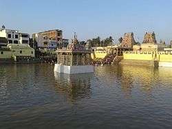 image of a temple tank with temple tower and complex in the background