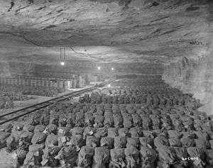 Row after row of sacks of gold, neatly stacked in a mine, with a mine rail running down the middle.