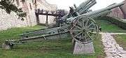 a pale green-painted wheeled artillery piece on a concrete plinth