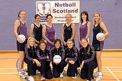 Wearing purple, the netball team is standing in two rows