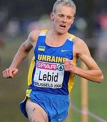 A man in a Ukraine vest grimaces while he runs.