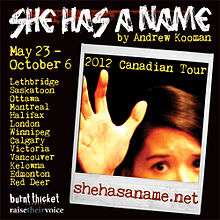 A black square with the words "SHE HAS A NAME" in white letters at the top and an instant photograph below the words, depicting part of a face and a hand