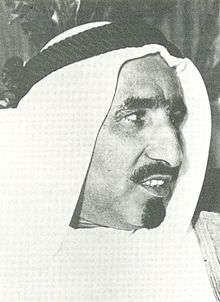 Black-and-white right-facing profile portrait of a man wearing a Van dyke beard and a keffiyeh.