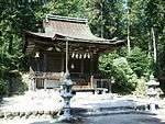 A small wooden building with a roofed, raised veranda with a handrail