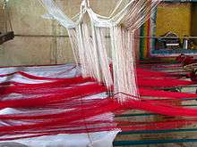 weaving with threads hanging from a loom