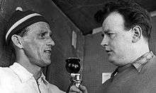 Sixten Jernberg, left, is being interviewed by another man, on the right, who is holding a microphone.