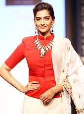 Kapoor walking the ramp in red dress.