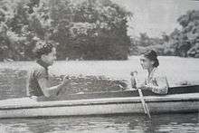 A black-and-white photograph of a man and a woman in a boat