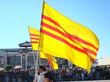 Parade marchers with South Vietnamese flags: three horizontal red stripes on a gold background