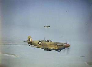 A Spitfire with SAAF markings, flying against a blue sky