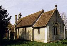 A simple rendered church with a red tiled roof and a bellcote