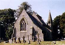 A flint church with steep roofs and an octagonal belfry and spire