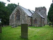 The east end of a stone church with a gabled north vestry and a squat battlemented west tower