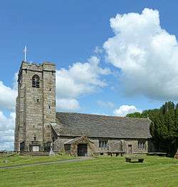 A stone church seen from the south, with a low body and relatively large tower.