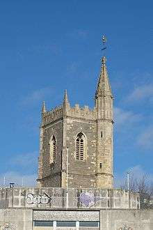 Tower of ruined St Mary le Port with derelict building in foreground