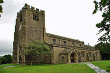 A stone church seen from the south-west with a large battlemented tower