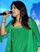 Sunidhi Chauhan performing on stage wearing a green dress