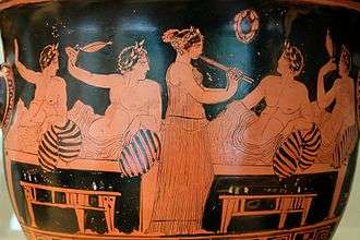Photograph of an Attic red-figure vase, showing a female flute player and male guests at a symposium.