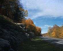 A divided highway going past a rock outcrop in autumn