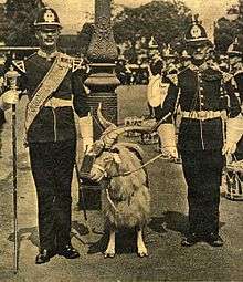 sepia-tone, a goat with a head-dress between two soldiers
