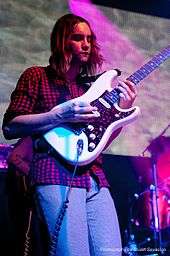 Kevin Parker playing the guitar during a concert.