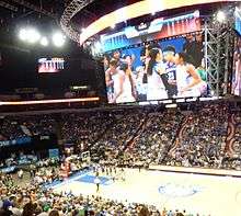 Photo from above the court showing large Daktronics scoreboard dominating the room, with Maya Moore's ponytail and Renee Montgomery on the video display and Sylvia Fowles, Natasha Howard and Jia Perkins visible at left. They were standing near the bench, not on the court at the time.