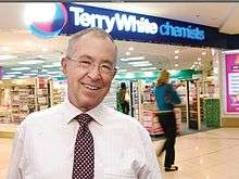 Terry White in front of a Terry White Chemists store