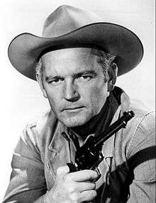 Profile of a man in cowboy garb holding a six-shooter.