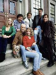 The cast sitting on stairs outside a door