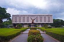 A concrete building is seen behind a statue