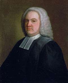 A middle-aged man in black robes with white collar bands and a white wig