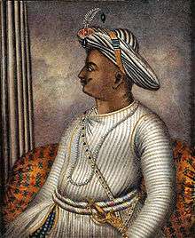 Side portrait of man in turban wearing knitted tunic with gold sword