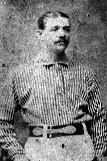 A man standing in his baseball uniform.