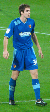 A young man wearing blue shirt, shorts and socks