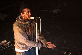 A man singing into a microphone with his hands together, on March 18, 2011 in Montreal, Quebec, Canada.
