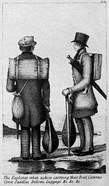 Two men carrying wooden sticks. One wears a small knapsack and the other carries a large furled umbrella.